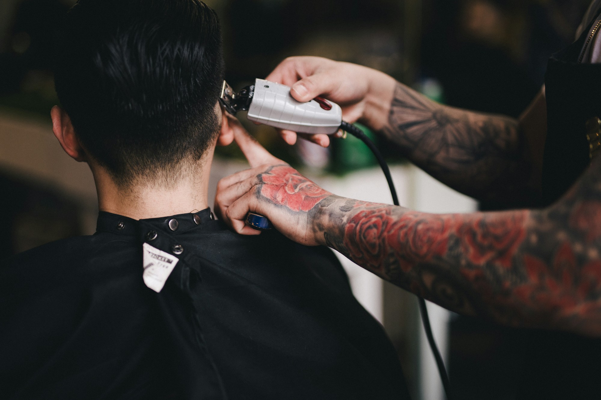 A barber using clippers on the back of a client's neck