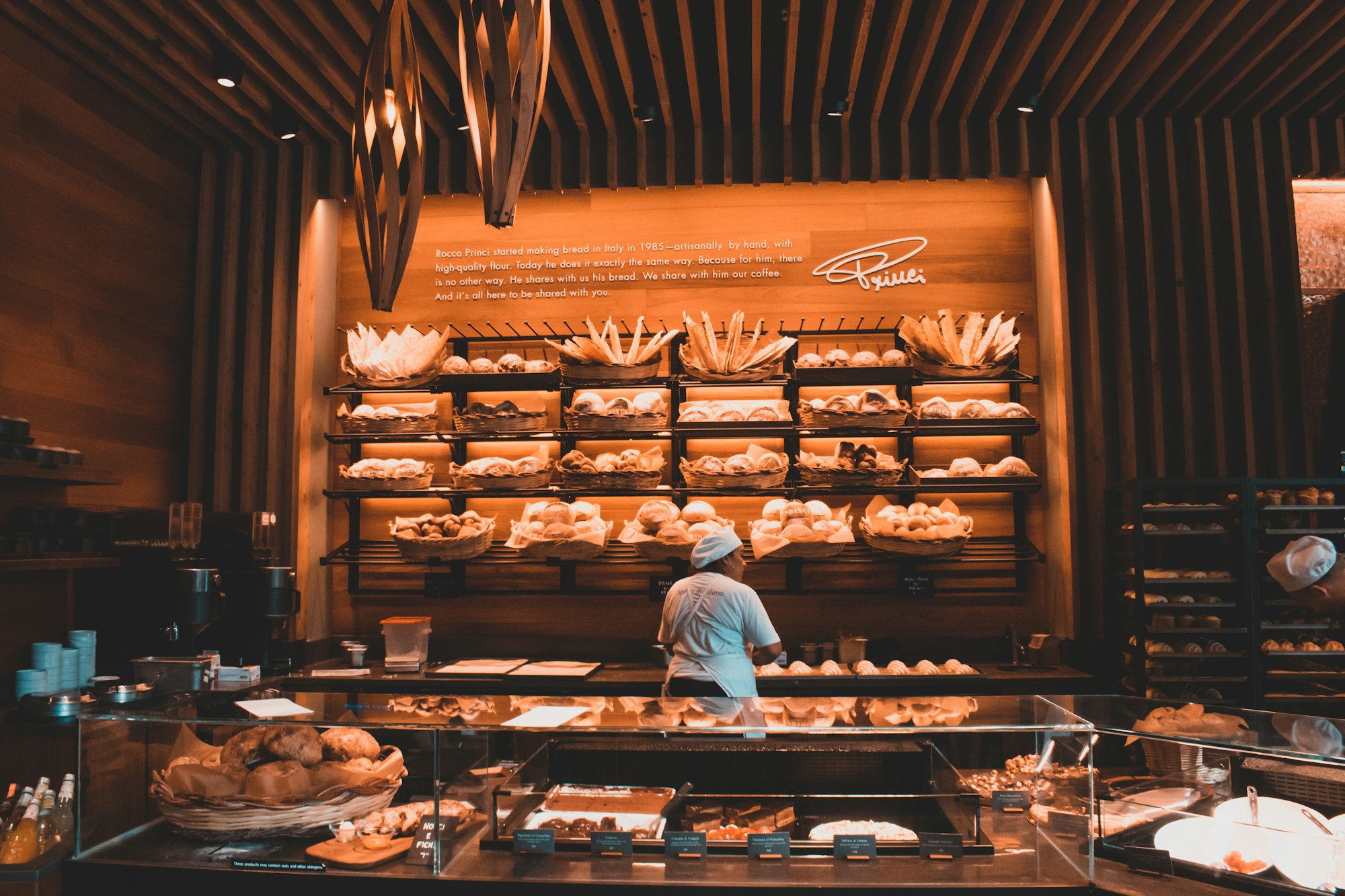 A baker behind a counter of fresh bread and pastries