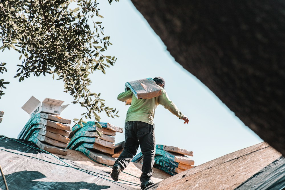 A roofer carrying a bundle of shingles
